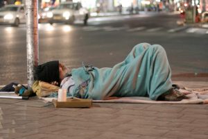 Homeless man sleeping in the street in UK being photographed in public