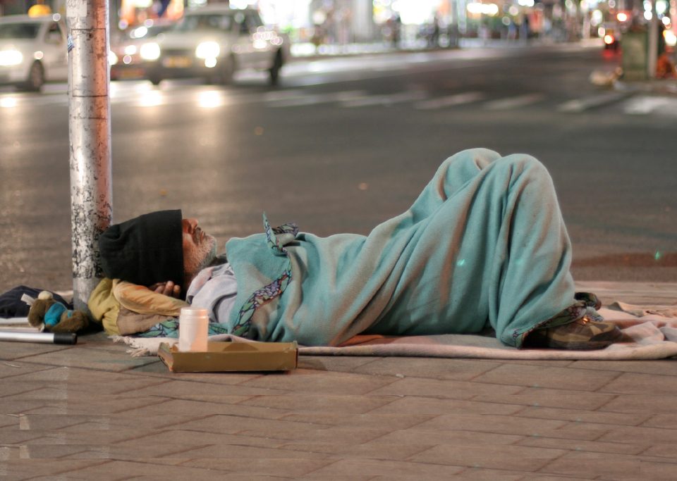 Homeless man sleeping in the street in UK being photographed in public