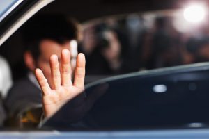 Man's hand blocking paparazzi from car