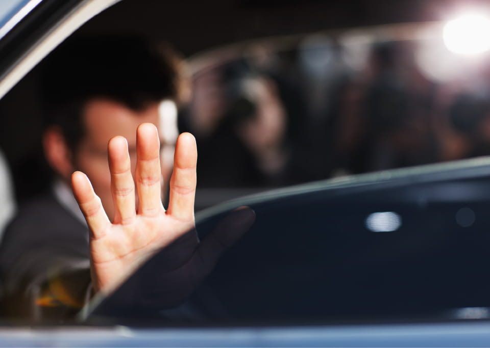 Man's hand blocking paparazzi from car