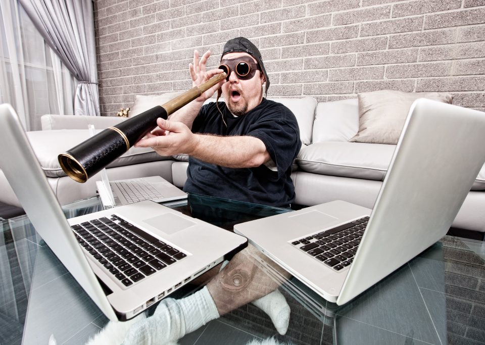 Mann mit Fernglas und Fliegerbrille schaut auf MacBook