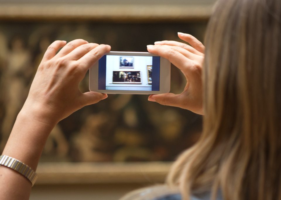 Frau fotografiert mit Smartphone Bild im Museum ab