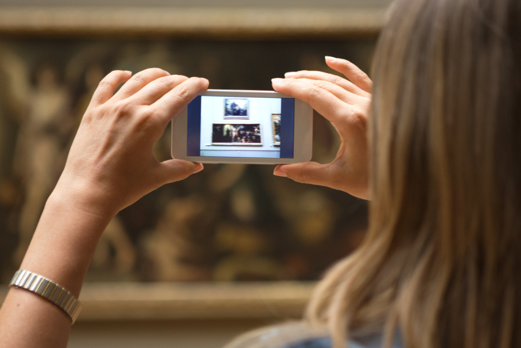 Frau fotografiert mit Smartphone Bild im Museum ab