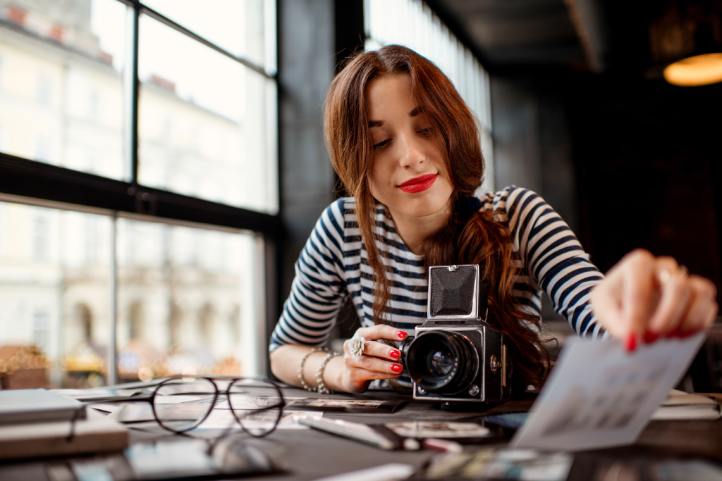 Frau mit Kamera schaut Fotos an