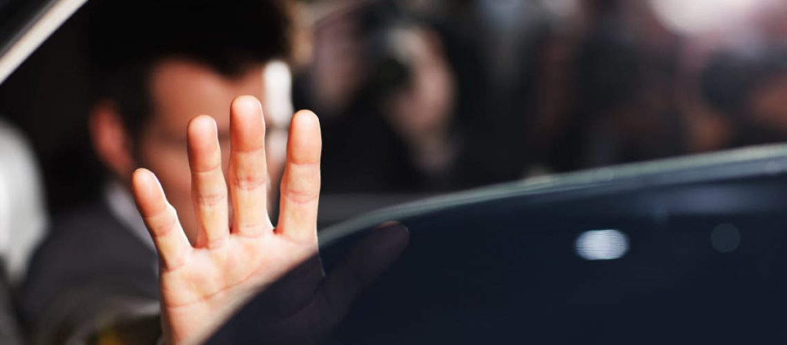 Man's hand blocking paparazzi from car